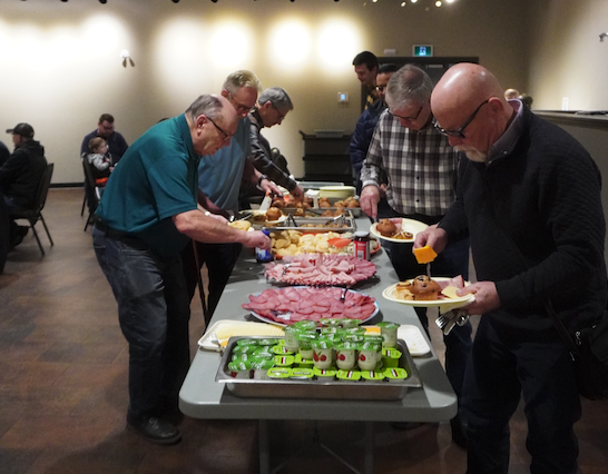A group of people standing around a buffet line